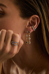 "Model wearing 14k gold blue sapphire and diamond drop earrings with a rough-textured finish, sapphire cuff and ring"