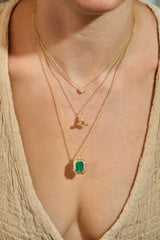 Mini Namaste praying hands pendant in 14K gold worn layered with diamond and emerald necklaces