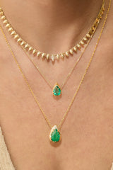 Pear-cut natural emerald drop necklace with hand-carved textured 14K yellow gold setting and delicate gold chain worn on neck with summer necklace and mystic emerald necklace