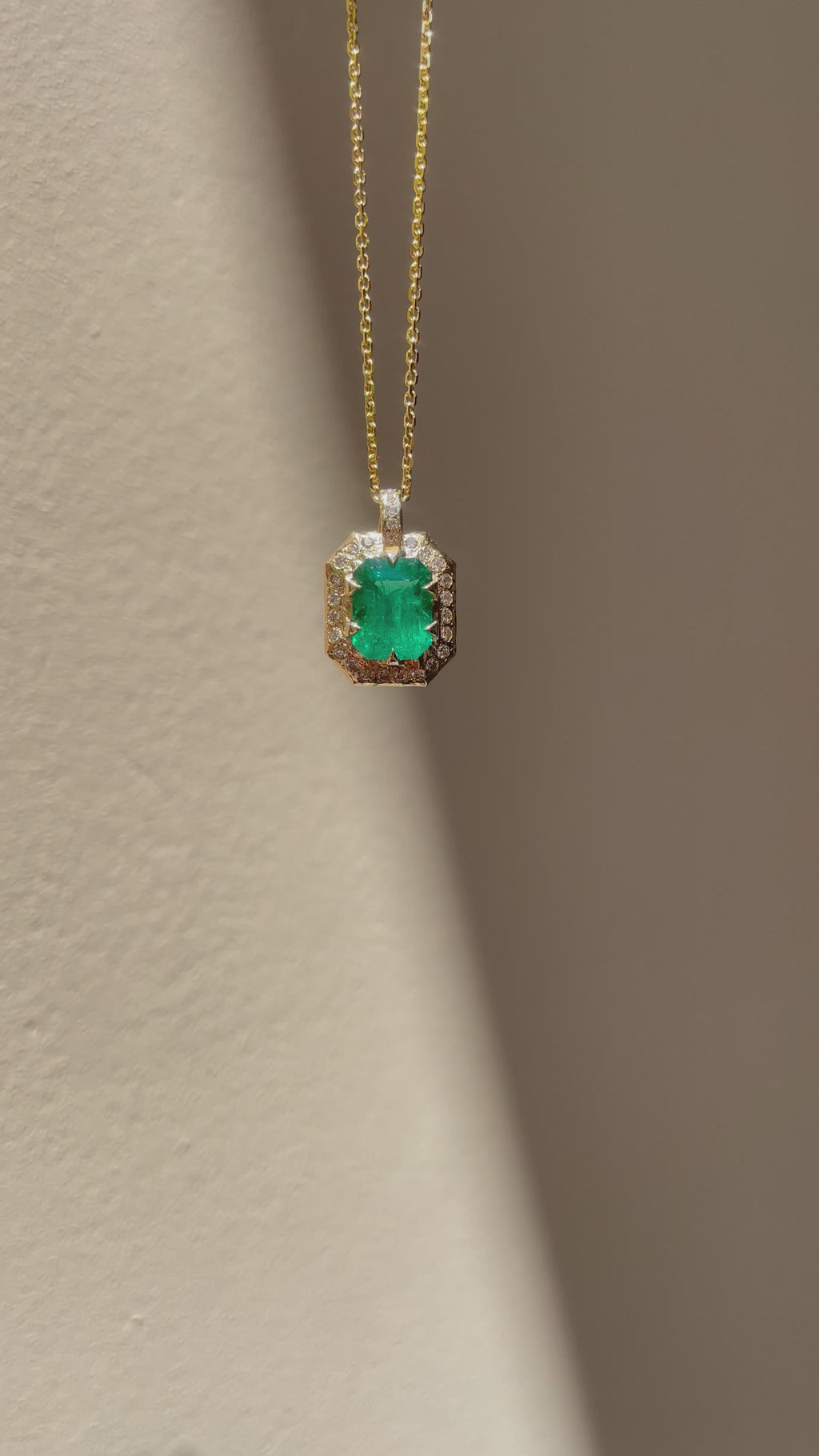 Emerald-cut natural emerald and diamond necklace in hand-carved 14K yellow gold, featuring a deep green center stone surrounded by natural diamonds.