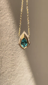 Pear-cut lagoon tourmaline and natural diamond necklace in hand-carved 14K yellow gold, featuring an Art Deco inspired geometric pendant.